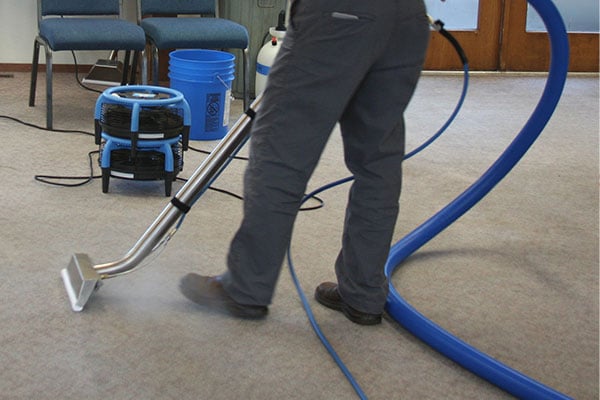 A person using a dri-eaz extraction tool to extract water from a carpet. 