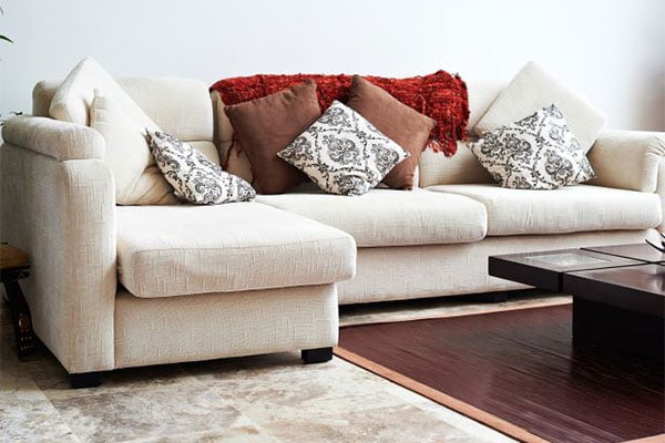 White couch with various styled throw pillows on a carpet.