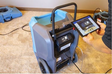 Dehumidifier with someone holding a tablet with the dehumidifier app open. 
