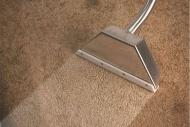 extraction wand being used on a dirty beige carpet. 