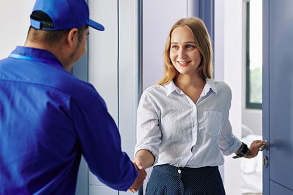 Woman in white shirt greeting a person in a blue shirt and hat. 