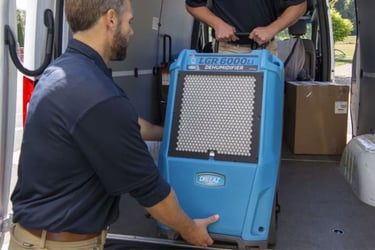 Man in blue polo shirt unloading a Dri-Eaz dehumidifier. 