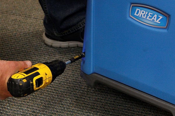 Someone using a drill for maintenance on a Dri-Eaz piece of equipment. 