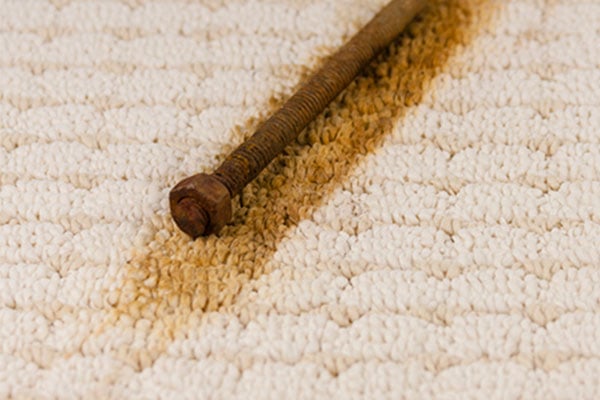 Rusty screw on beige carpet. Leaving behind a rust colored stain. 