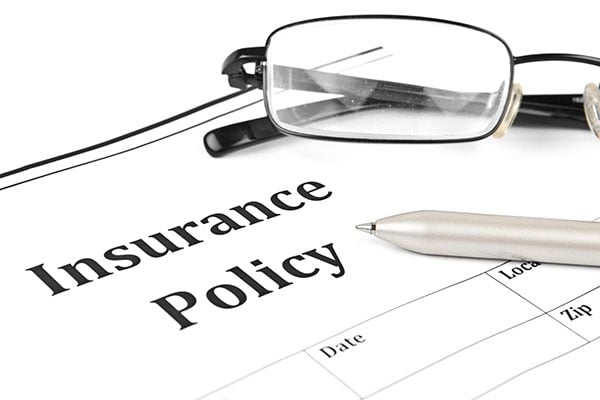 Glasses and pen sitting in an insurance policy paper