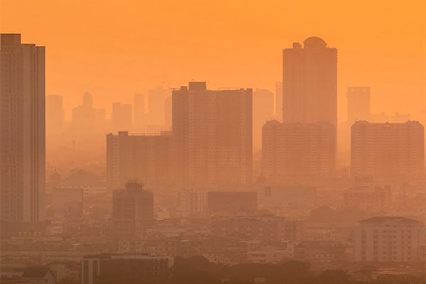 A city skyline covered in smoke making the whole scene have an orange hue over it. 