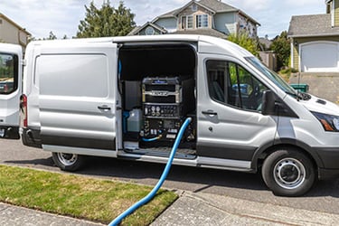 White truck with legend brands truckmount inside and a blue hose coming out. For water mitigation. 