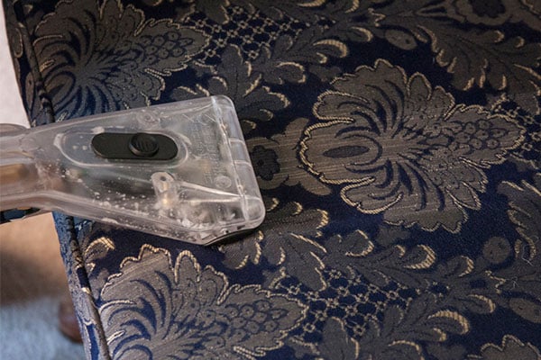 An extraction wand being used on upholstery to clean it. 