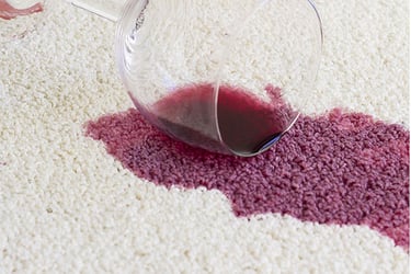 Spilled red wine staining a white carpet. 