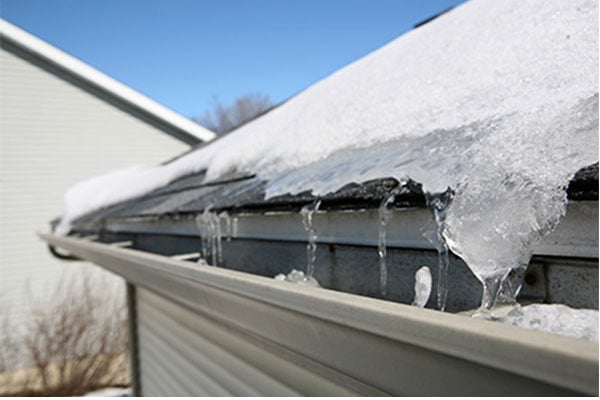 Roof with snow and ice melting into gutters. 